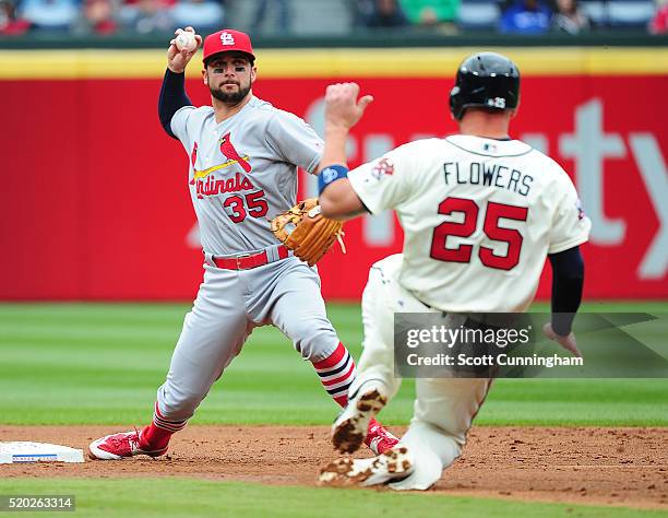 Greg Garcia of the St. Louis Cardinals turns a second inning double play against Tyler Flowers of the Atlanta Braves at Turner Field on April 10,...