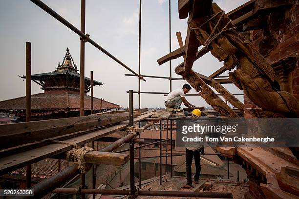 Construction workers, experienced in traditional Nepali style architecture, are standing on a scaffold and rebuild the top the major Taleju temple...