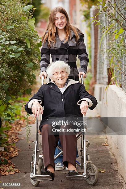 young girl pushing grandmother in wheelchair - pushing stockfoto's en -beelden