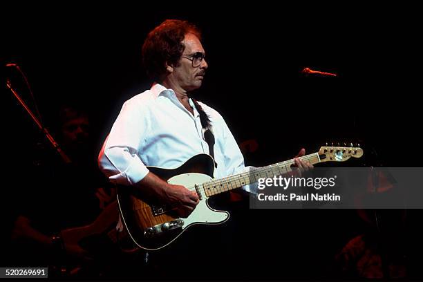 American musician Merle Haggard plays guitar as he performs onstage at the Poplar Creek Music Theater, Hoffman Estates, Illinois, August 16, 1983.