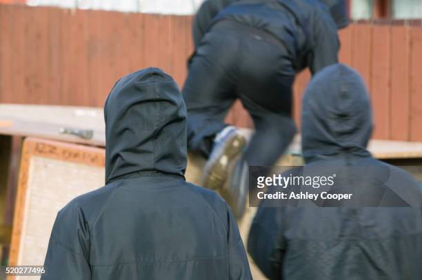 gang dressed in black hoodies - bande stock-fotos und bilder