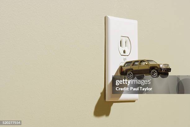 suv plugged into wall socket - sports utility vehicle stockfoto's en -beelden