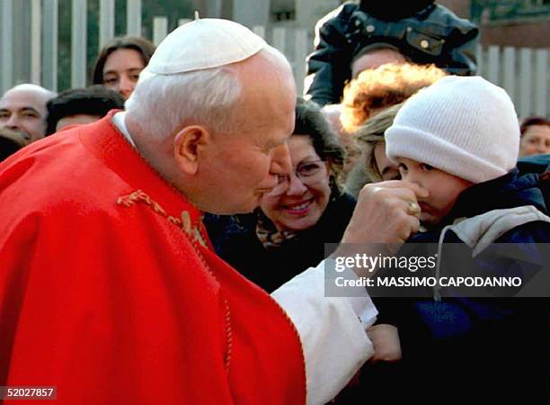 Pope John Paul II tweaks the nose of a child that came to watch the pontiff during his visit at St. Cleto Church in Rome 28 January. The Pope is...