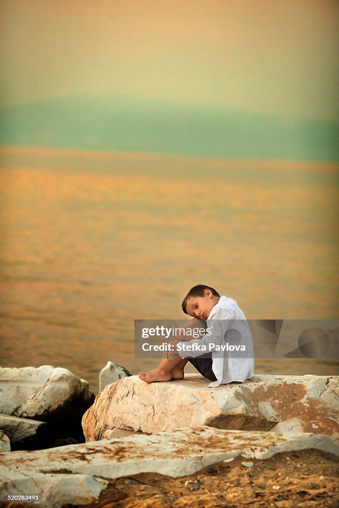 Boy sitting on a rock on the beach