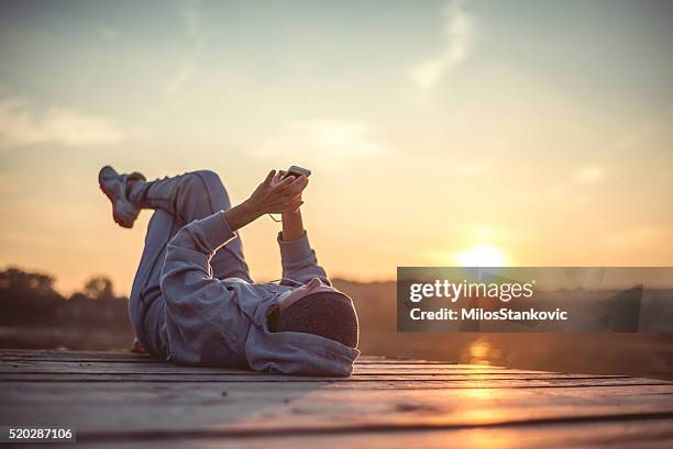resting and enjoy the sunset - woman smartphone nature stockfoto's en -beelden