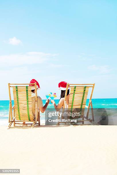 couple celebrating christmas vacation on beach with tropical drinks - hawaii christmas stockfoto's en -beelden