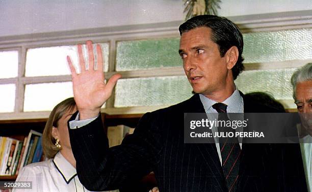 Former Brazilian President Fernando Collor de Mello waves to reporters 30 December 1992 after his press conference where he spoke about his...