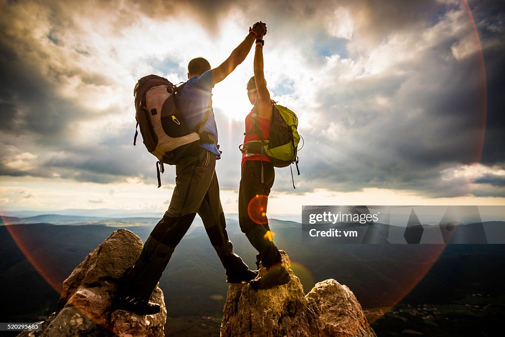 Couple on Top of a Mountain Shaking Raised Hands