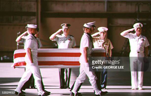 Military officers from each of the five branches salute in Hawaii 09 February 1993 a U.S. Flag-draped coffin reportedly containing the remains of a...