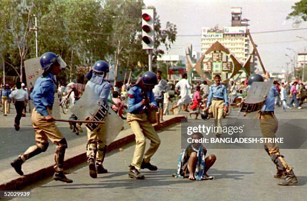 Street urchin begs for mercy as policemen raise rifles and batons to beat him 10 February, 1993 near Dhaka's Ggulistan district during a nationwide...