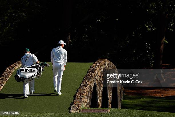 Danny Willett of England and Billy Foster, caddie for Lee Westwood of England, walk across the Hogan bridge to the 12th green during the final round...