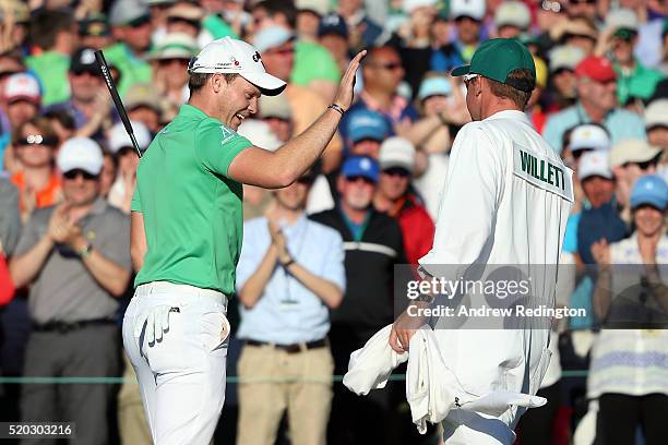 Danny Willett of England and caddie Jonathan Smart react on the 18th green after finishing during the final round of the 2016 Masters Tournament at...