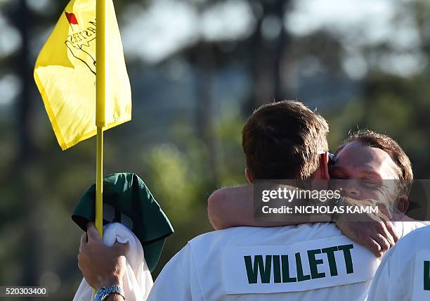 England's Danny Willett embraces his caddie Jonathan Smart after putting on the 18th green during Round 4 of the 80th Masters Golf Tournament at the...