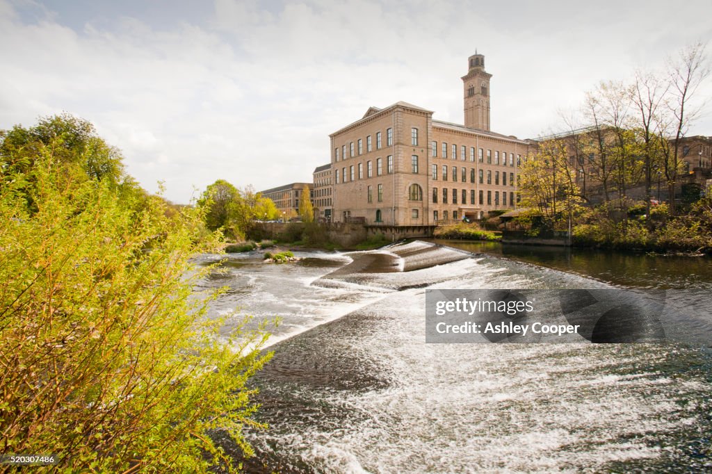 Salts mill in Saltaire, Yorkshire, UK and a weir on the River Aire.