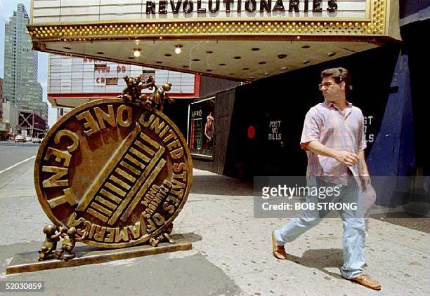 Pedestrian walks past a sculpture of a giant penny on New York's 42nd Street 9 July 1993 as two dozen artists, architects and designers transform a...