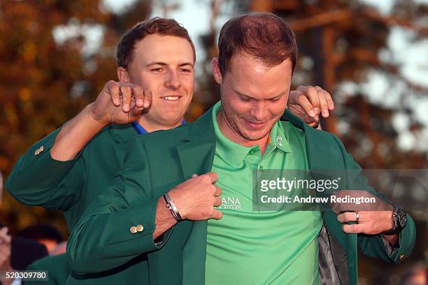 Jordan Spieth of the United States presents Danny Willett of England with the green jacket after Willett won the final round of the 2016 Masters...
