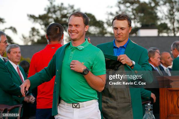 Jordan Spieth of the United States presents Danny Willett of England with the green jacket after Willett won the final round of the 2016 Masters...