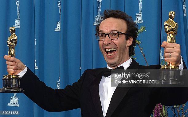 Actor Roberto Benigni of Italy holds his two Oscars for Best Foreign Language Film and Best Actor for "Life is Beautiful" at the 71st Annual Academy...