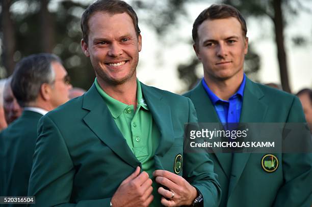 England's Danny Willett smiles wearing the Green Jacket as US golfer Jordan Spieth looks on at the end of the 80th Masters Golf Tournament at the...