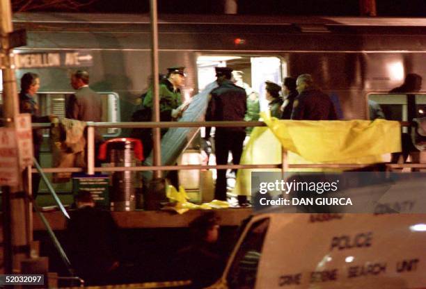 Police officers and emergency workers bring in stretchers to remove the bodies of shooting victims on a Long Island Rail Road commuter train in New...