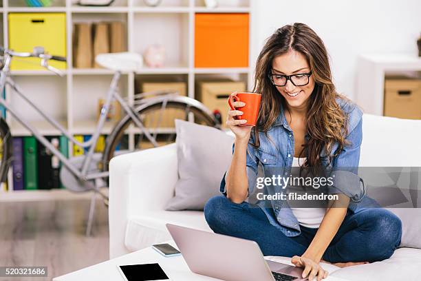 frau mit laptop zu hause - woman using smartphone with laptop stock-fotos und bilder