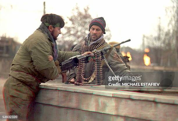 Chechen fighters position a machine gun during a pause in fighting in downtown Grozny 10 January as flames burst from a damaged gas pipeline burn in...