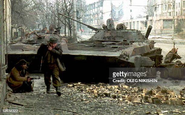 Chechen fighter runs for cover as another hides behind a destroyed Russian tank during fighting in Grozny, 08 January. Russian forces resumed...