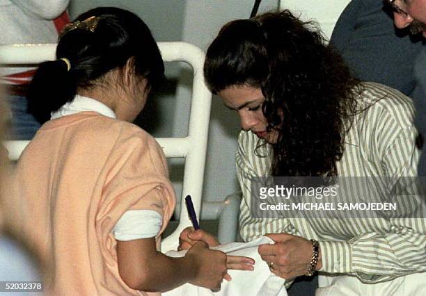 Figure skater Nancy Kerrigan signs an autograph for a young fan 08 January 1994 after the conclusion of the 1994 US Figure Skating Championships....