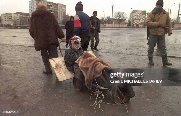 Chechen youngster severely wounded by artillery shelling in downtown Grozny is dragged on a self-made cart by two civilians 08 January in search of a...