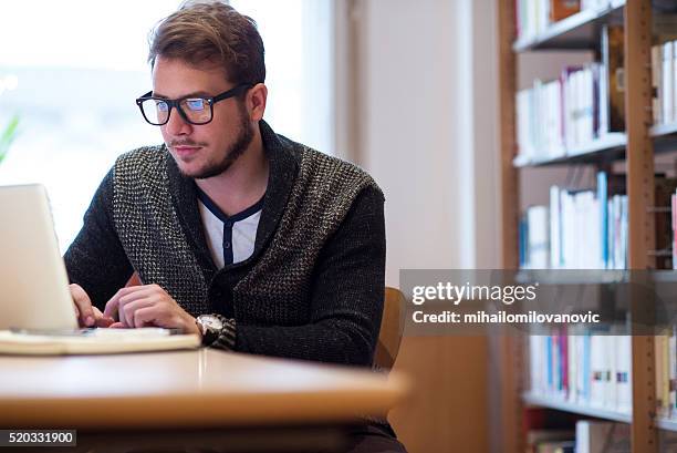 young man in library - laptop work search stockfoto's en -beelden