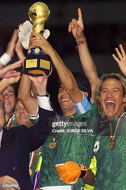 Mexican players Claudio Suarez and Luis Hernandez lift the 1999 Confederations Cup championship trophy after winning the tournament by defeating...