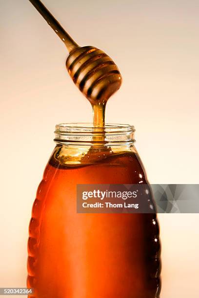 fresh honey dripping from dipper - honinglepel stockfoto's en -beelden