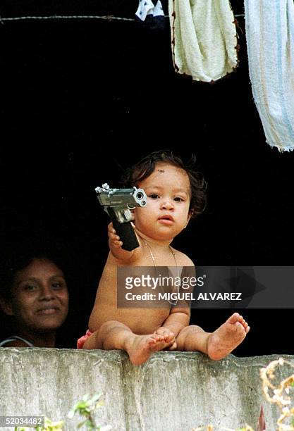 Child plays with toy pistol in a neighborhood where needy families live, 16 September 1999, in Managua. Un nino juega con una pistola de juguete, el...