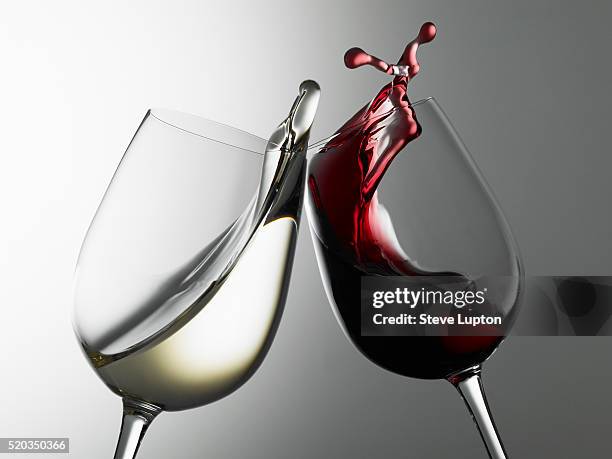 raising a toast of red and white wines - weinglas stock-fotos und bilder