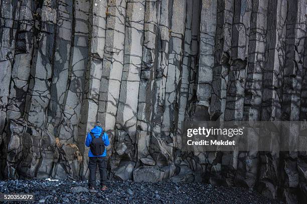a man with volcanic basalt cliff at reynisfjara, iceland - geoloog stockfoto's en -beelden