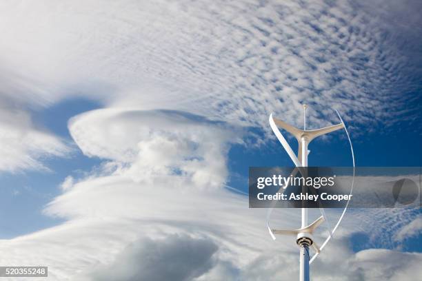 a composite image of high level cloud patterns with a vertical axis wind turbine. - stratus stock pictures, royalty-free photos & images