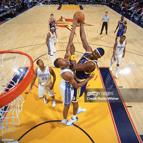 Clifford Robinson of the Golden State Warriors battles for a shot against Marcus Camby of the Denver Nuggets during a game at The Arena in Oakland on...