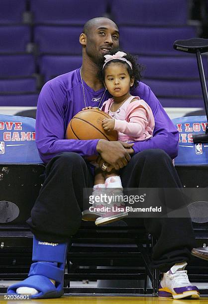 Kobe Bryant of the Los Angeles Lakers sits with his daughter, Natalia, before the game against the Minnesota Timberwolves as he recovers from an...