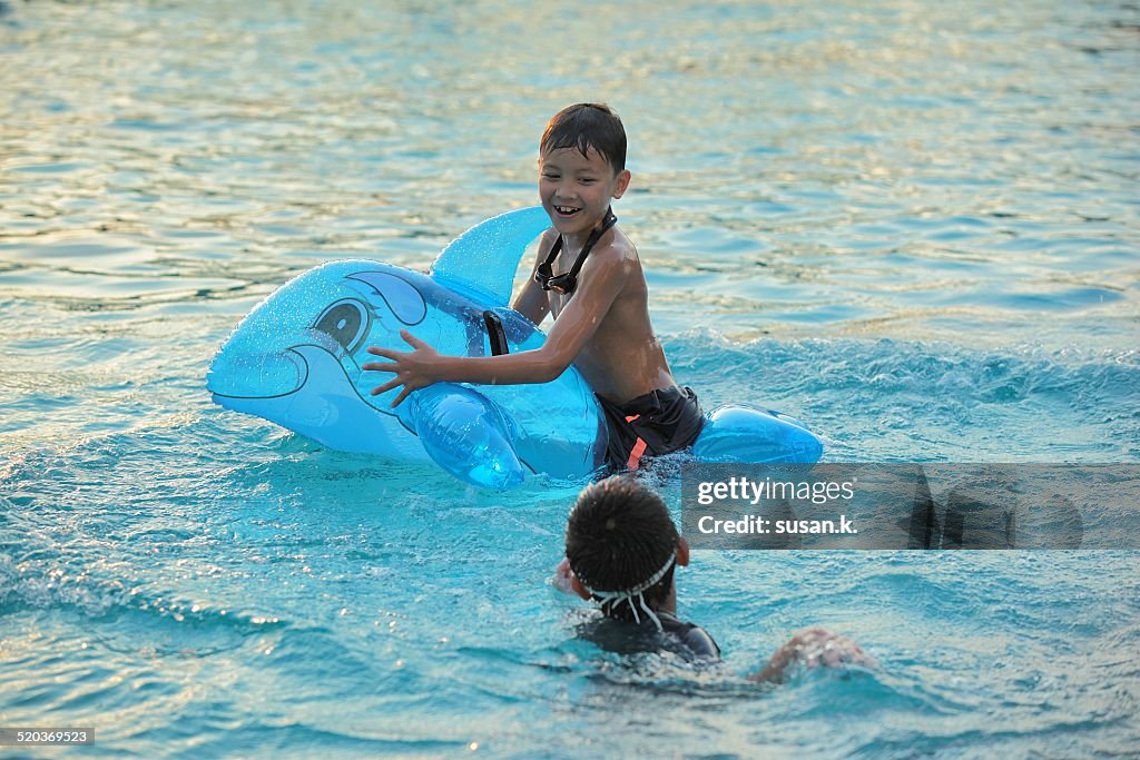 Two boys playing dolphin balloon in the pool