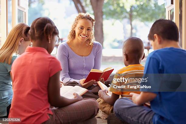 librarian reads aloud to a group of children - christendom stockfoto's en -beelden