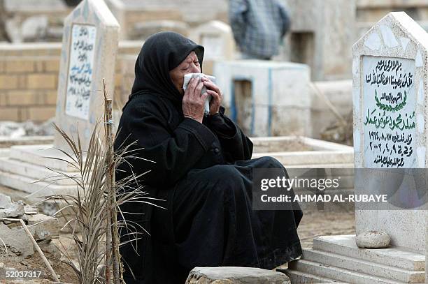 An Iraqi woman sits crying at the side of a grave at the Imam Ghazali cemetery in Baghdad 20 January 2005, for the start of Eid al-Adha. Muslims all...