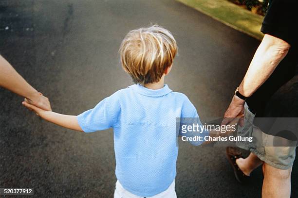 son walking between parents hand in hand - personne non reconnaissable photos et images de collection