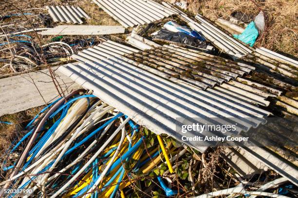 illegally dumped asbestos sheeting with plastic wire sheath left by metal thieves - asbest stockfoto's en -beelden