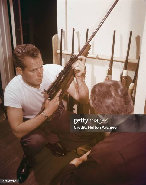 American actor Charlton Heston shows off his gun collection to an unidentified man, 1950s.