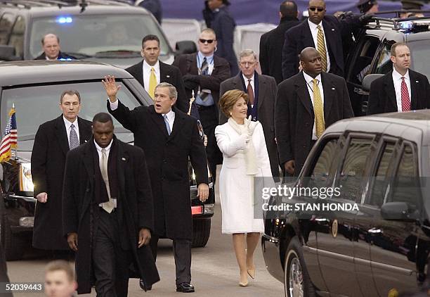 Surrounded by Secret Service agents, US President George W. Bush and his wife Laura wave as they walk in the inaugural parade down Pennsylvania...
