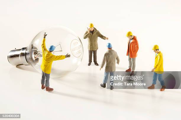 utility worker figurines installing light bulb - figurines stock-fotos und bilder