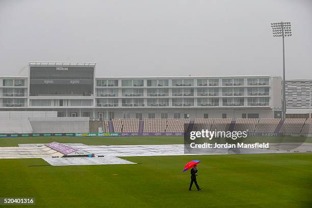 Presenter walks the field as rain delays the start of play during day two of the Specsavers County Championship Division One match between Hampshire...