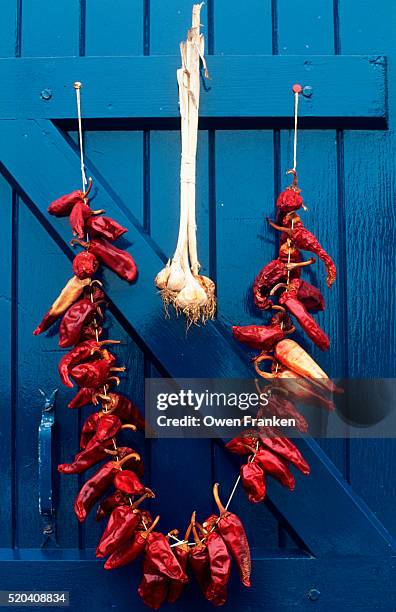 red peppers and garlic hang on a blue door - france chili stock pictures, royalty-free photos & images