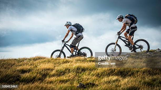 bikers riding on a mountain trail - mountainbike stock pictures, royalty-free photos & images