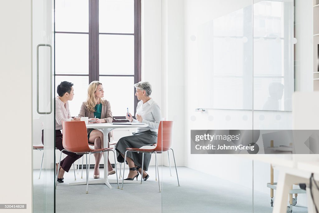 Three women sitting at table in modern office
